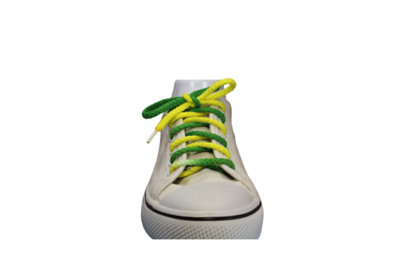 a white shoe with a braided shoelace which is green and yellow