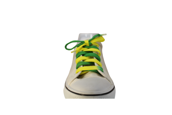 a white shoe with a flat shoelace which is dyed green on one side, yellow on the other