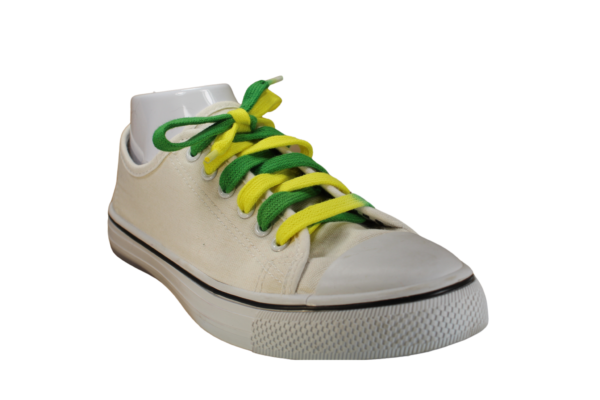 a white sneaker at a right angle with a shoelace that is half green and half yellow