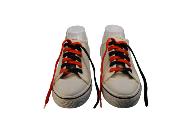 a pair of untied flat shoelaces dyed black and orange