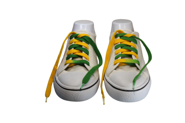 a pair of untied flat custom made green and gold shoelaces