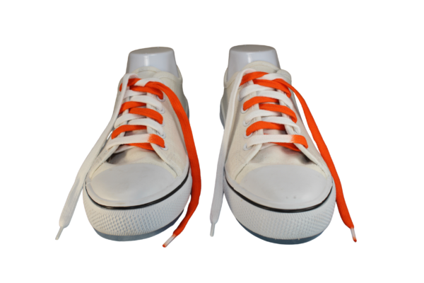 Orange and white flat untied shoelaces in a white sneaker