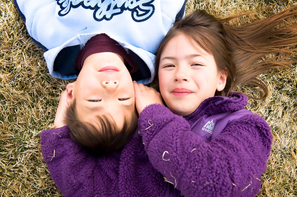 two kids on the ground with faces next to each other