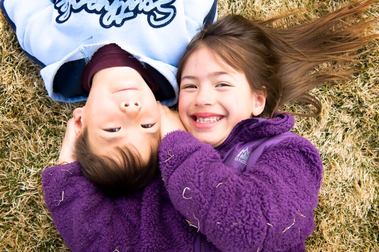 1 young boy and 1 young girl on the ground with their heads together